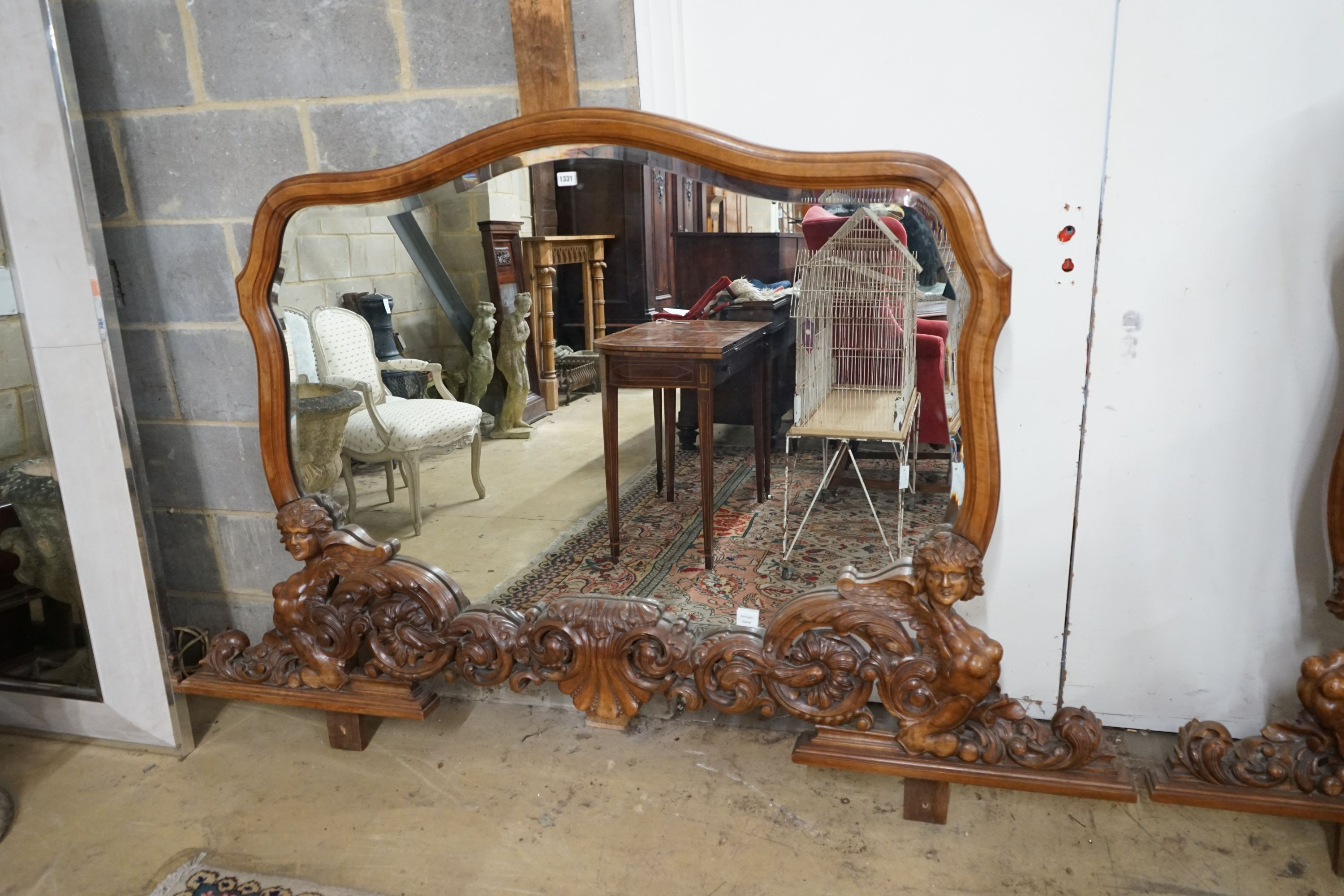 A near pair of Italian style carved walnut overmantel mirrors, decorated with winged figures, scrolls and scallop shells, larger width 200cm, height 152cm